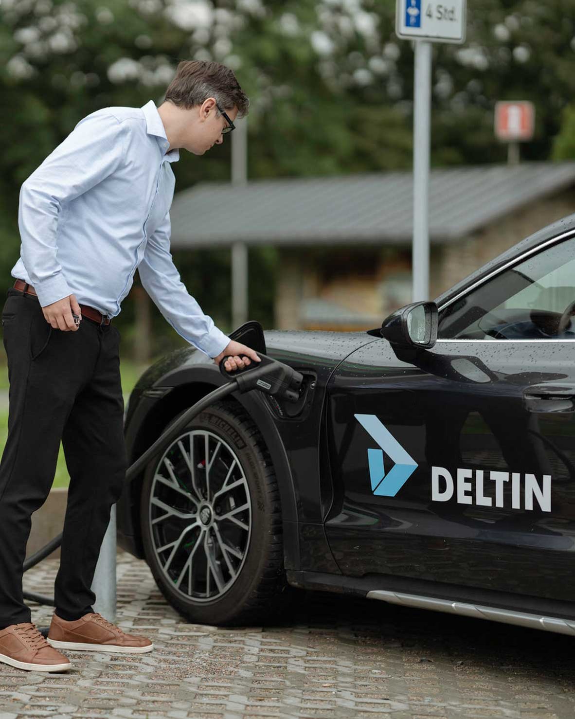 Mann steckt DC-Stecker in E-Auto