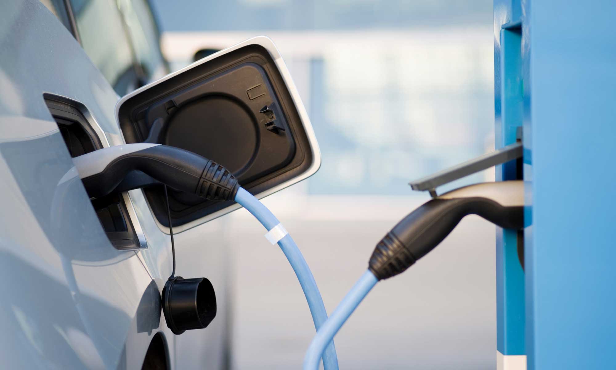 Blaues E-Auto wird in Garage aufgeladen